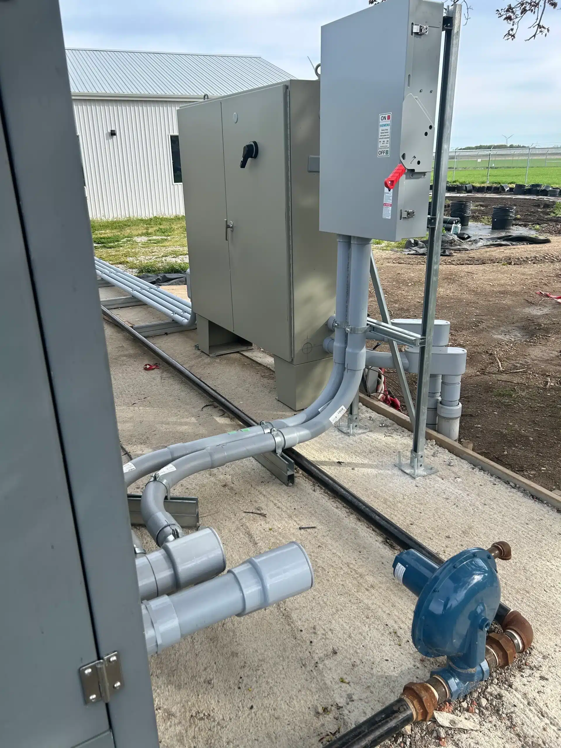 "Industrial outdoor electrical setup with multiple metal conduits and a large electrical distribution box