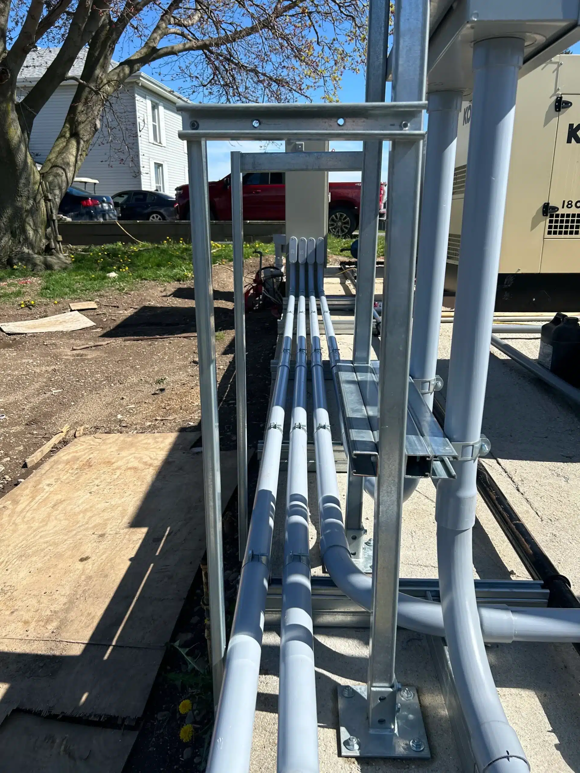 Multiple PVC conduits mounted on a metal structure outdoors, showing detailed piping and support systems