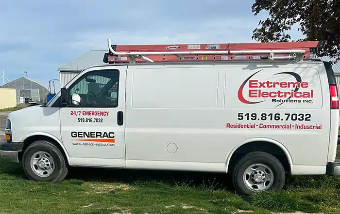 A parked white van with company logos for electrical services and emergency contact information.